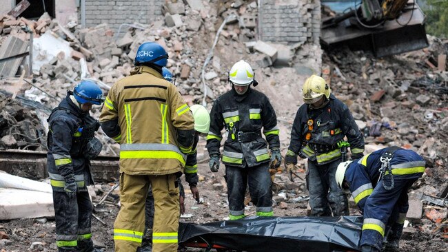 Workmen fix a pipe in the crater left by a Russian missile strike near Taras Shevchenko National University in Kyiv on Monday. Nineteen people were killed by the strikes across Ukraine