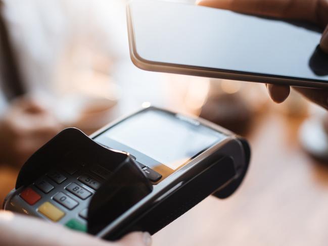 Example of digital wallet payment system in cafe: closeup of male customer swiping his smartphone over terminal paying with his credit card via phone