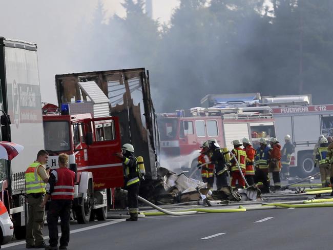 Rescue workers stand beside a burnt-out coach on the motorway A9 near Muenchberg, southeastern Germany. Picture: AP