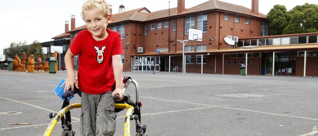 Tom Roach at age five with his old walker at Kew Primary School. Picture: Paul Loughnan