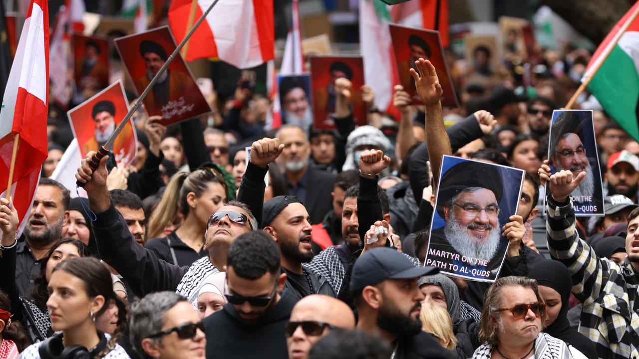 People hold up pictures of Hezbollah leader Hassan Nasrallah at a protest at Town Hall in Sydney on Sunday Picture: NewsWire / Damian Shaw