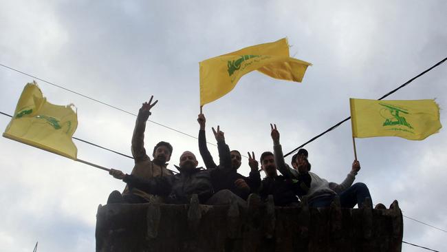 Men wave the flag of Hezbollah as they arrive in the southern Lebanese city of Nabatieh on November 27, as displaced people make their way back to their homes in the south of Lebanon after a ceasefire between Israel and Hezbollah took effect. Picture: AFP