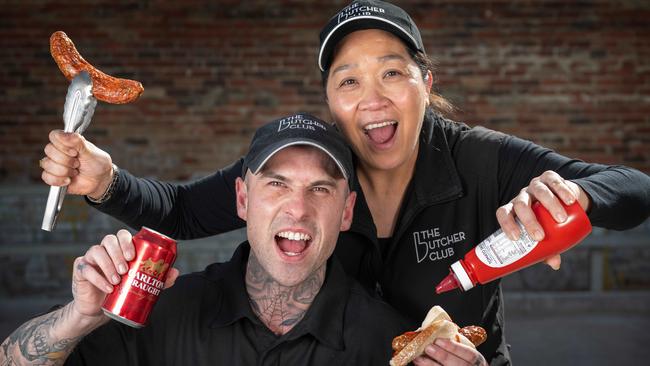 The Butcher Club Richmond’s Jenny Lai and Corey Robinson get into the finals fever with beer-spiked snags in bread and some Carlton Draught. Picture: Tony Gough