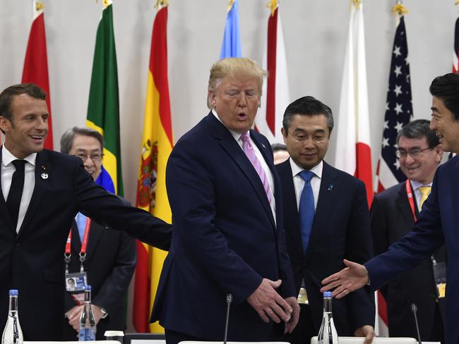 French President Emmanuel Macron puts his hand on President Donald Trump as Japanese Prime Minister Shinzo Abe stands at right before a working session at the G-20 summit in Osaka, Japan, Friday, June 28, 2019. (AP Photo/Susan Walsh)