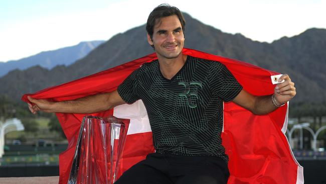 Roger Federer poses with his trophy and the Swiss flag after his win at Indian Wells.