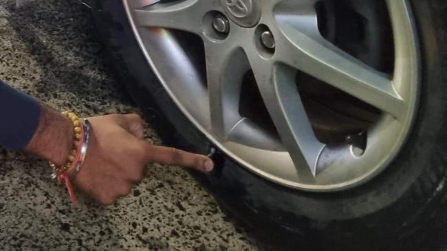 Ms Daniel pointing to her slashed tyre caused by a pothole.
