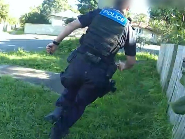 A police officer runs to intercept a teenager accused of a series of break-ins across Brisbane