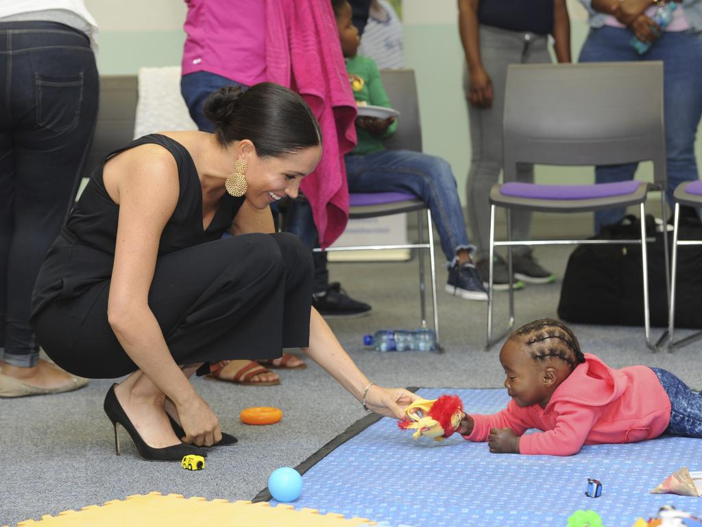 Britain's Meghan Duchess of Sussex gets don to play with a child at the event. Picture: Henk Kruger / African News Agency Pool via AP.