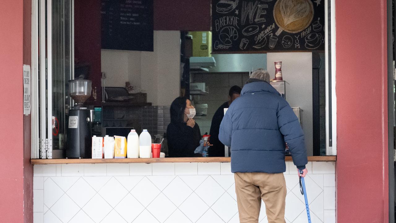 A customer waits outside a coffee shop that swapped to takeaway only due to Covid-19 restrictions.