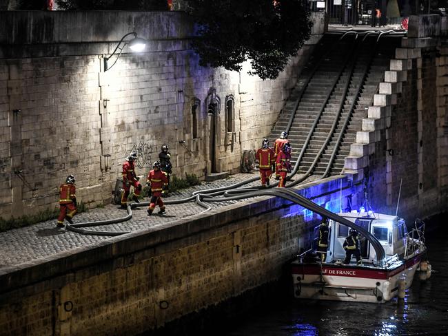 Firefighters assemble their hoses as they gather at the River Seine near Notre-Dame de Paris Cathedral as flames engulf the roof of the cathedral on April 15, 2019, in the French capital Paris. (Photo by STEPHANE DE SAKUTIN / AFP)