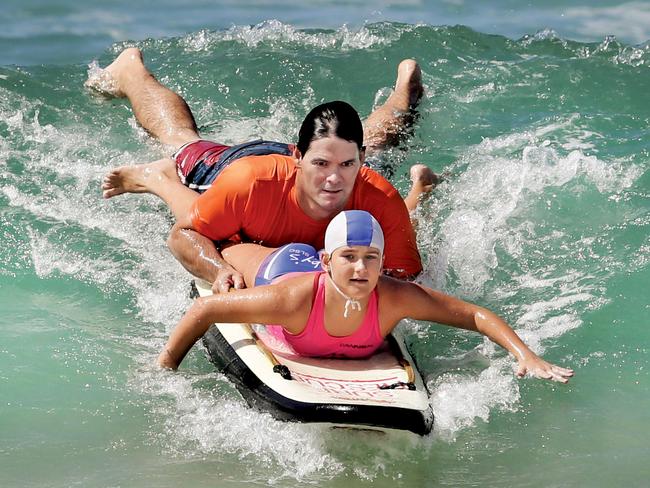 Nick Marshall, a physio from SurfLife Physio, is a nippers coach. He's starting a new initiative giving special needs kids the opportunity to participate in nippers activities. Nick catches a wave with Matilda Adams, 11, who has special needs. Pic by Luke Marsden.