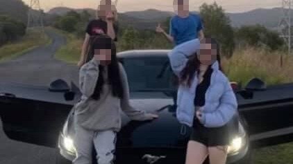 Youths posing with a Ford Mustang allegedly stolen from an address at Helensvale in a photo posted to social media.