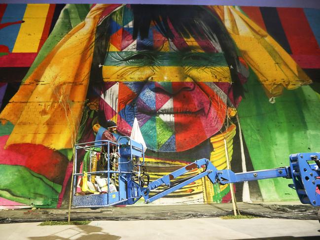 A worker descends along a section of a mural depicting indigenous faces being created by Brazilian graffiti artist Eduardo Kobra and assistants in the revamped Port District on July 20, 2016 in Rio de Janeiro, Brazil. The 32,000-square-foot mural, titled ‘We Are All One’, is being painted to represent cultural diversity across continents and will be completed shortly before the start of the Rio 2016 Olympic Games on August 5. (Photo by Mario Tama/Getty Images)