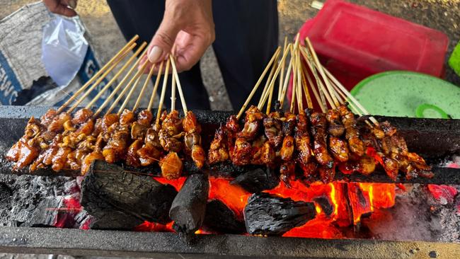 Chicken satay cooked over flames. Picture: Jenny Hewett
