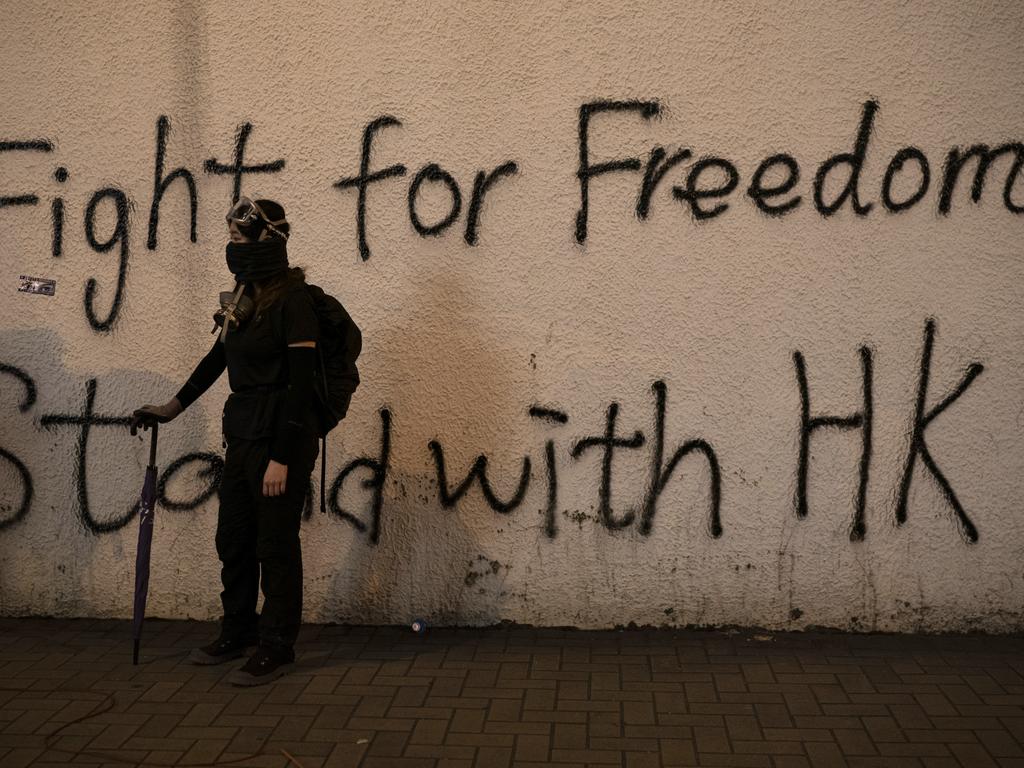 A black-clad protester stands by graffiti on the wall in Hong Kong. Picture: AP