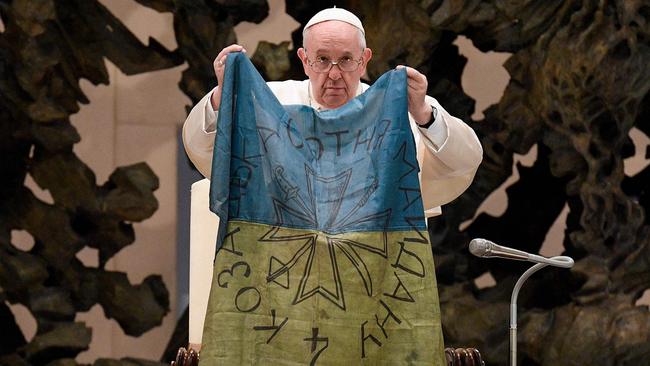 Pope Francis holding a flag of Ukraine that comes from the city of Bucha during the weekly general audience in The Vatican. Picture: VATICAN MEDIA / AFP