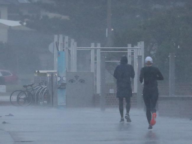 Joggers attempted a morning run at Sydney’s Bondi Beach on Friday despite the saturating weather. Picture: John Grainger