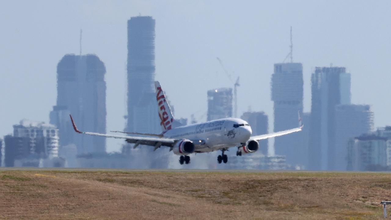 Plane landing at Brisbane airport with the city in the background. Picture: Liam Kidston