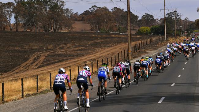 Women’s TDU riders pass a burned paddock on Friday. Picture: Tim de Waele/Getty Images