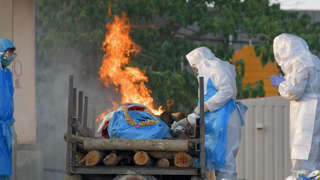 Family members and relatives wearing protective gear perform final rites of a victim who died of COVID-19. Picture: Manjunath Kiran/AFP