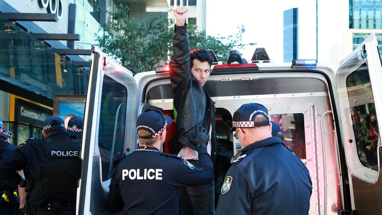 Protester Connor Brooks raises his arm as he is loaded into a police vehicle after being arrested as environmental protesters stopped traffic in the Brisbane CBD on Monday. Picture: AAP/Image Sarah Marshall