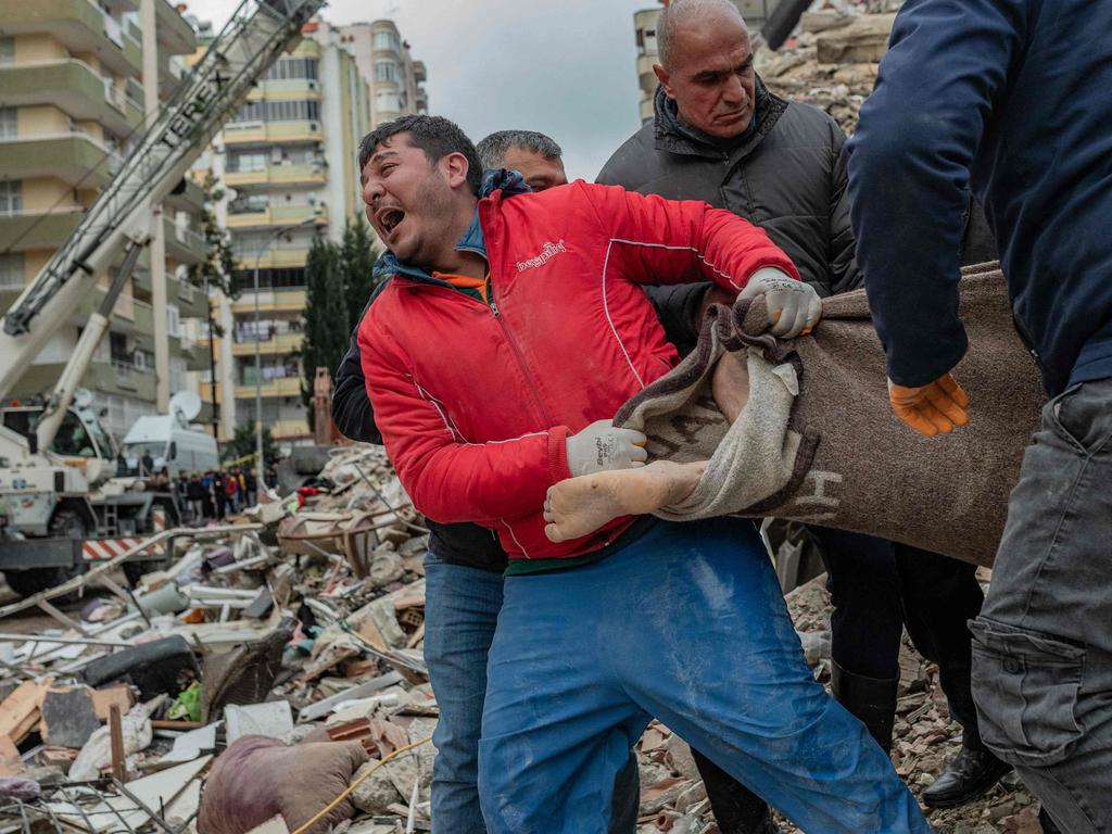 Devastated rescuers reacts carry a body found in the rubble in Adana. Picture: AFP