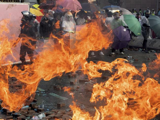 Protesters watch as a fire burns during a confrontation with police at Hong Kong Polytechnic University in Hong Kong. Picture: AP Photo/Ng Han Guan