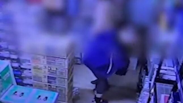 CCTV footage of a woman putting a can of alcohol in her bag.