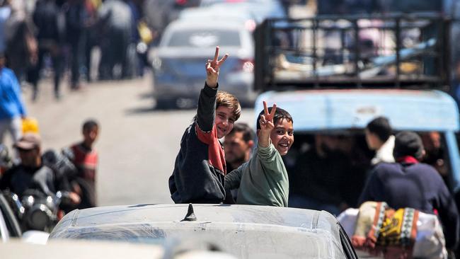 Two boys strike an optomistic tone as they’re driven along a street in Rafah on Tuesday. Picture: AFP