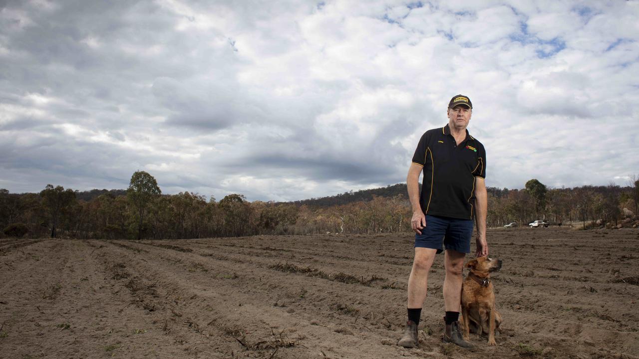 Lewis Perkins with Cass the red cattle dog, on land that normally would have a green crop growing. In Stanthorpe, Queensland in June, 2019 it was still dirt. Picture: Russell Shakespeare