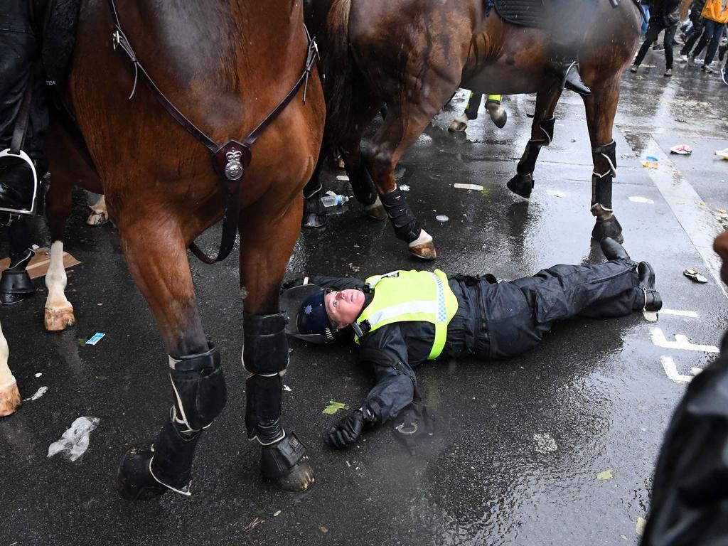 A mounted police officer lays on the road after being unseated from her horse. Picture: Daniel Leal-Olivas/AFP