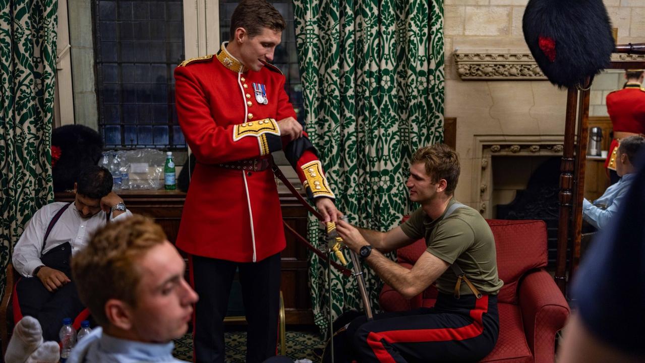 One guard is seen napping between shifts while another gets help with his uniform. Picture: UK Ministry of Defence