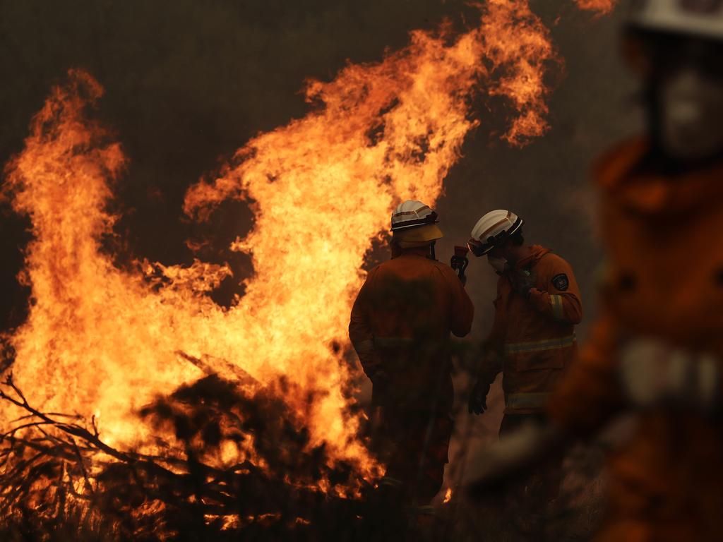 Tasmania Fire Service personnel put out a spot fire threatening a home on Donnelleys Road, Geeveston. Picture: LUKE BOWDEN