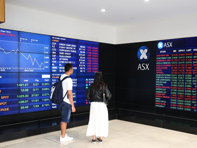 People look at an electronic board displaying stock information at the Australian Securities Exchange. Picture: Getty Images.