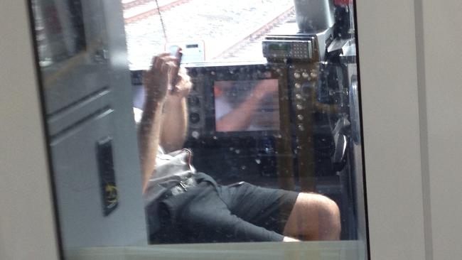 A guard on a Monday morning service from the CBD to Homebush takes an opportunity to sit down and look at a mobile device as the train travels between Central and Redfern stations. Pic: Supplied