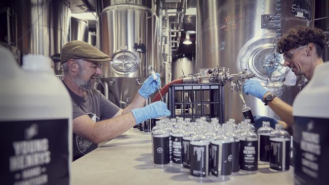 Young Henrys founder Richard Adamson, left, and brewer Ben Holdstock pour and pack the alcohol-sanitiser liquid into bottles.