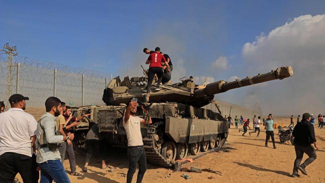 Palestinians take control of an Israeli Merkava battle tank after crossing the border fence with Israel from Khan Yunis in the southern Gaza Strip on October 7, 2023. Picture: AFP