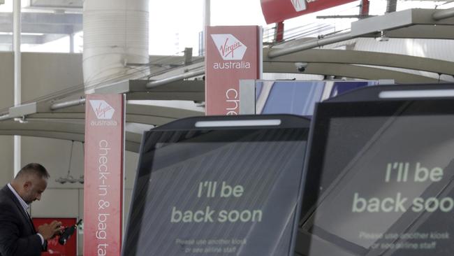 A Virgin Australia worker uses his phone at the check-in counters at Sydney Airport in Sydney in April. Picture: AAP