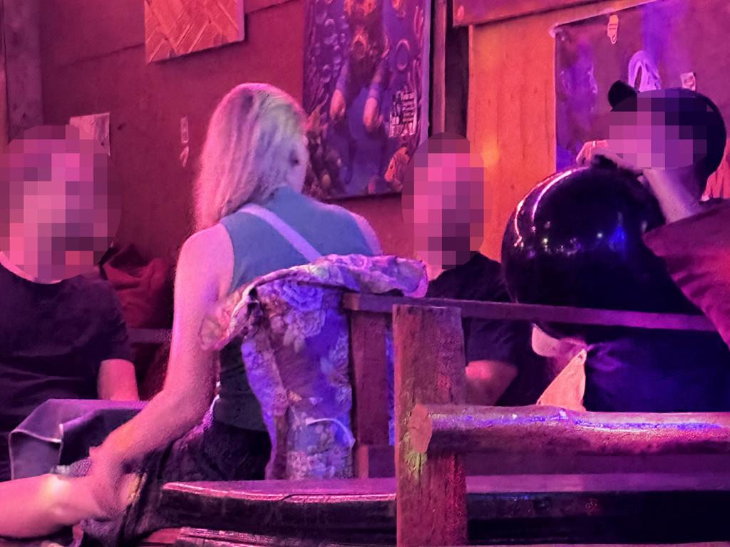 Patrons at the bar inhale gas from a large black balloon.