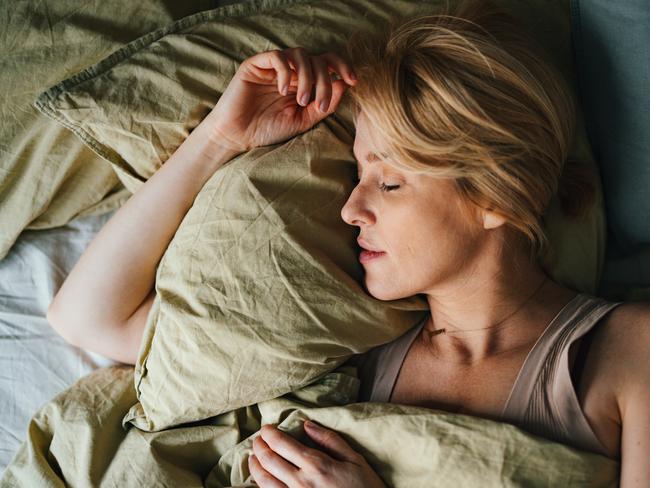 Top view of a beautiful blonde woman sleeping in bed. She looks peaceful and fast asleep.