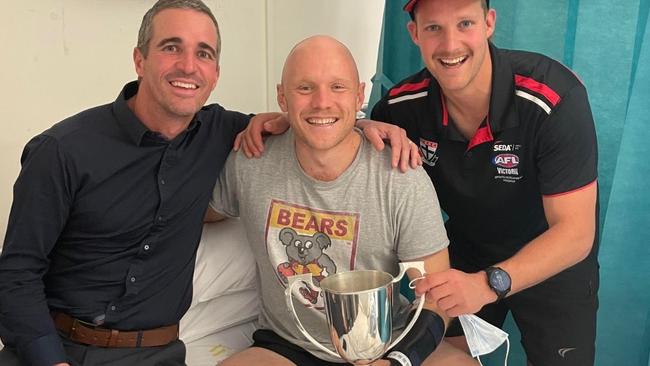 Mornington player Jimmy Cameron holds the premiership cup in the Alfred, with coaches Leigh McQuillen (left) and Josh Newman.