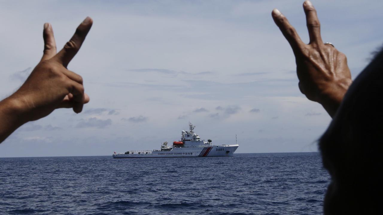 In this photo taken March 29, 2014, Philippine crewmen gesture towards a Chinese Coast Guard ship as they block them from entering Second Thomas Shoal in the South China Sea. The Permanent Court of Arbitration (PCA) issued its ruling Tuesday, July 12, 2016, in The Hague in response to an arbitration case brought by the Philippines against China regarding the South China Sea, saying that any historic rights to resources that China may have had were wiped out if they are incompatible with exclusive economic zones established under a U.N. treaty. (AP Photo/Bullit Marquez)