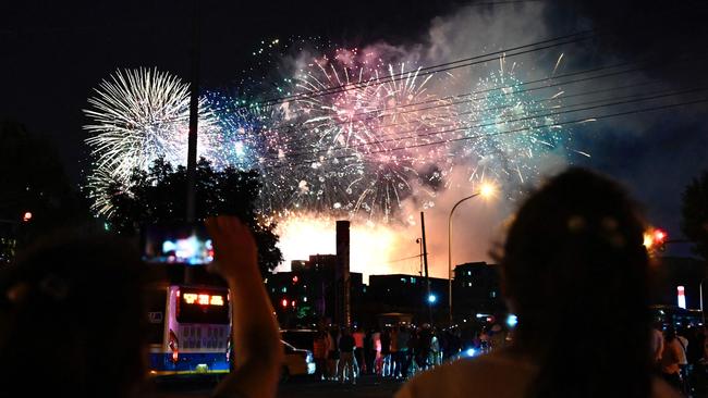 People take photos as fireworks explode overhead during a rehearsal of a performance marking the 100th anniversary of the founding of the Communist Party, at the Bird’s Nest national stadium in Beijing. Picture: AFP