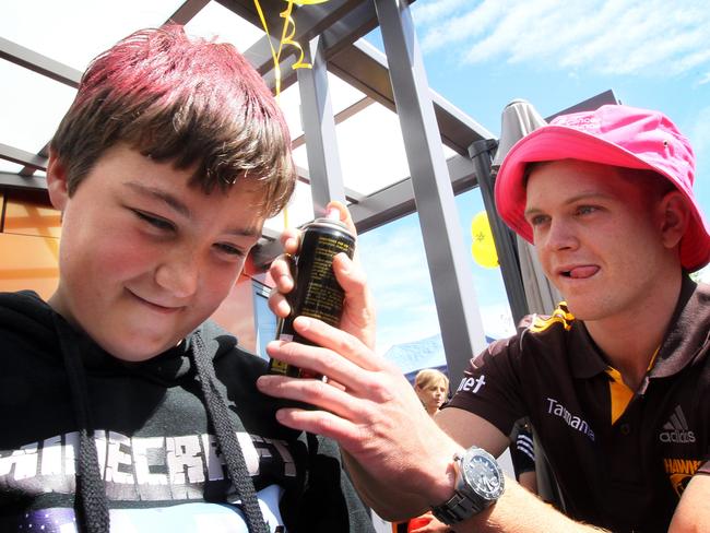 Bailey Jordan, of Devonport, has his hair sprayed pink by Hawthorn player Taylor Duryea in Launceston. Picture: ROSS MARSDEN