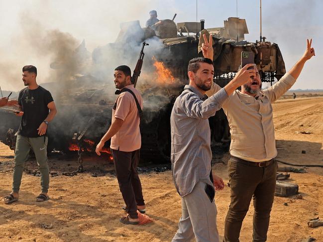 TOPSHOT - Palestinians take control of an Israeli tank after crossing the border fence with Israel from Khan Yunis in the southern Gaza Strip on October 7, 2023. Barrages of rockets were fired at Israel from the Gaza Strip at dawn as militants from the blockaded Palestinian enclave infiltrated Israel, with at least one person killed, the army and medics said. (Photo by SAID KHATIB / AFP)