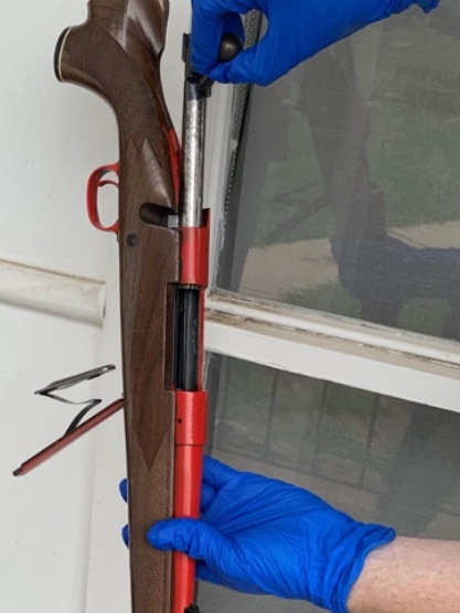 An officer holds up the rifle allegedly found at a home in Riverwood. Picture: NSW Police