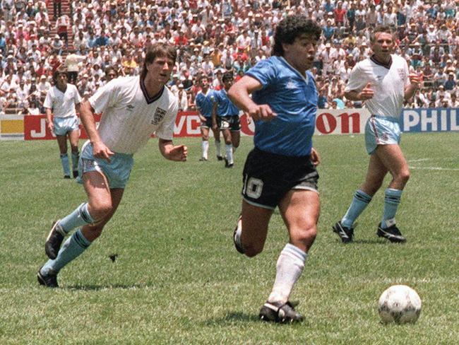 (FILES) In this file photo taken on June 22, 1986 Argentinian forward Diego Armando Maradona runs past English defenders Terry Butcher (L) and Terry Fenwick (2nd L) on his way to scoring his second goal during the World Cup quarterfinal soccer match between Argentina and England.Argentina advanced to the semifinals with a 2-1 victory.  AFP PHOTO - Argentinian football legend Diego Maradona passed away on November 25, 2020 (Photo by STAFF / AFP)