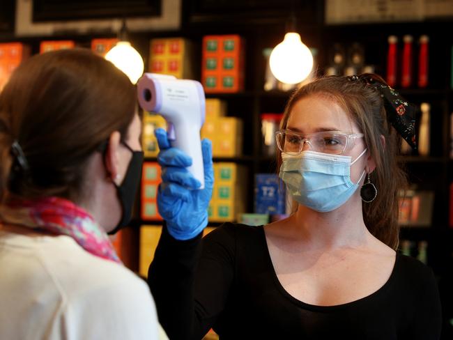 SYDNEY, AUSTRALIA - AUGUST 06: T2 Store Manager Alex Grivas tests the temperature of a customer at Broadway Shopping Centre on August 06, 2020 in Sydney, Australia. Mirvac Retail has mandated masks be worn by all their staff in shopping centres as part of their health and safety precautions in response to the ongoing COVID-19 pandemic. While face masks have not been made mandatory in New South Wales, state Premier Gladys Berejiklian has urged residents across the NSW to wear face masks when on public transport, in the supermarket, or in enclosed spaces where social distancing is difficult. (Photo by Lisa Maree Williams/Getty Images)