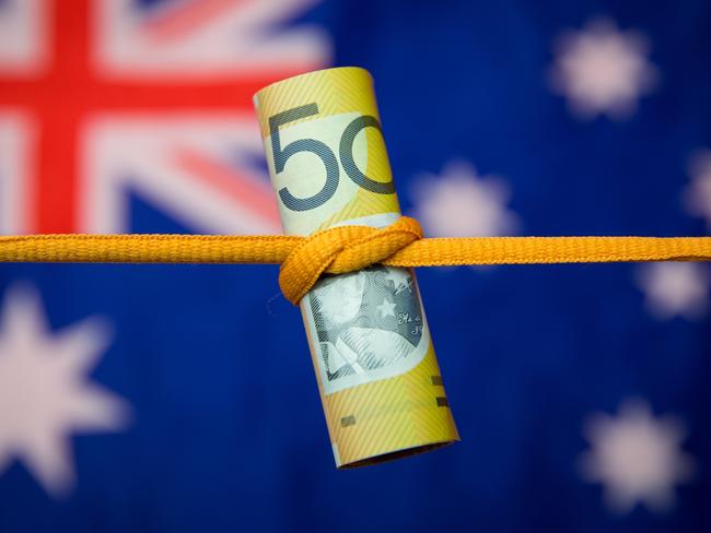 Studio shot close up of an Australian dollar note tied in a knot with the Australian flag as a background. Mortgage home loan money stress generic