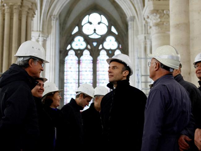 French President Emmanuel Macron (C), wearing a working helmet, talks with conservation experts as he visits the restoration site at the Notre-Dame de Paris Cathedral, which was damaged in a devastating fire four years ago, in Paris, France, April 14, 2023. (Photo by SARAH MEYSSONNIER / POOL / AFP)